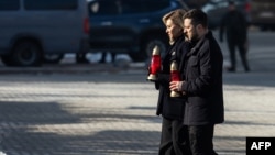 Ukrainian President Volodymyr Zelenskyy (right) and first lady Olena Zelenska hold candles during a ceremony to mark the third anniversary of Russia's all-out invasion of Ukraine, on Independence Square in Kyiv on February 24.