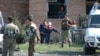 Security forces stand guard outside a school in Beslan while emergency crews work inside in 2004 photo.