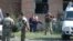 Security forces stand guard outside a school in Beslan while emergency crews work inside in 2004 photo.