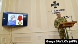 Ukrainian Security Service deputy chief Viktor Kononenko (right) speaks during a press conference as a picture of Kirill Vyshynsky is seen on a screen in Kyiv on May 15.