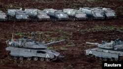 Israeli tanks and armored personnel carriers prepare near the Lebanese border.