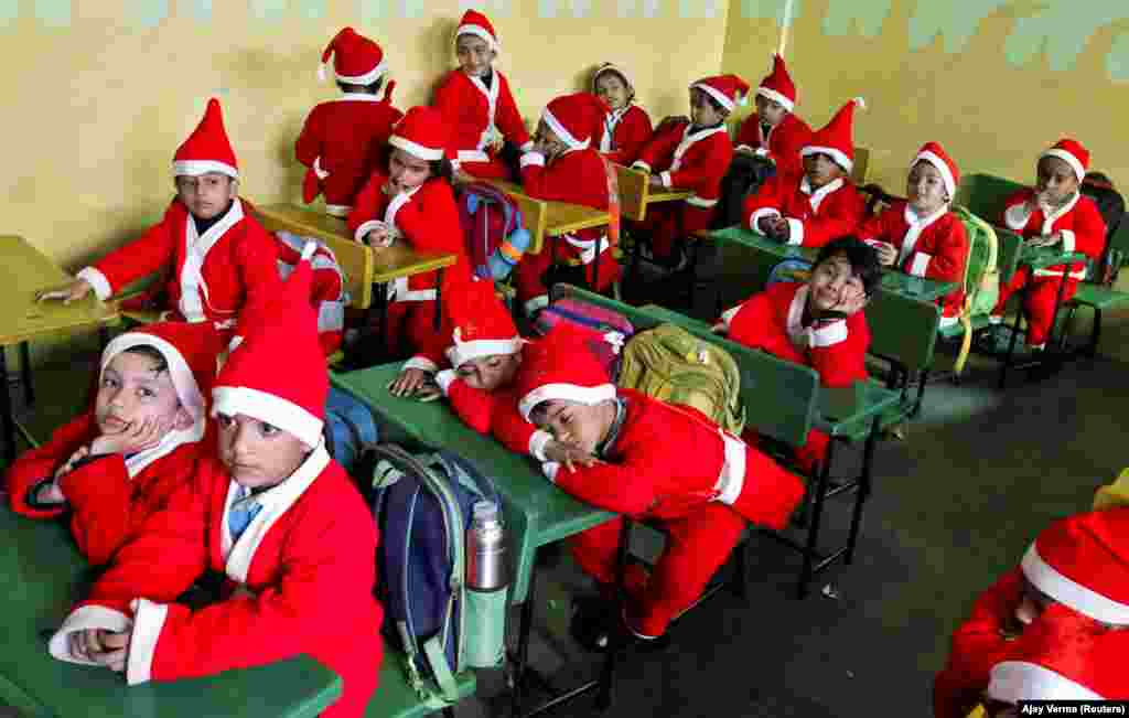 Children dressed in Santa Claus costumes sit inside a classroom before participating in Christmas celebrations at a school in Chandigarh, India. (Reuters/Ajay Verma)