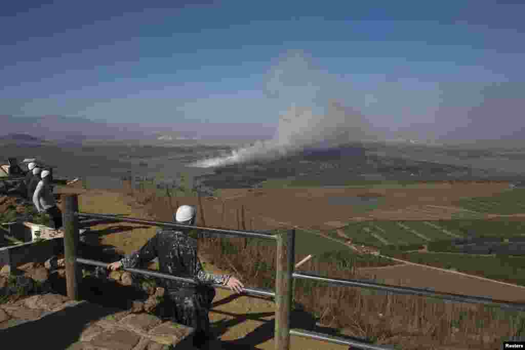 Druze men look at smoke rising on the Israeli-controlled side of the line dividing the Israeli-occupied Golan Heights from Syria following fighting near the Quneitra border crossing on August 27. (Reuters/Ronen Zvulun)