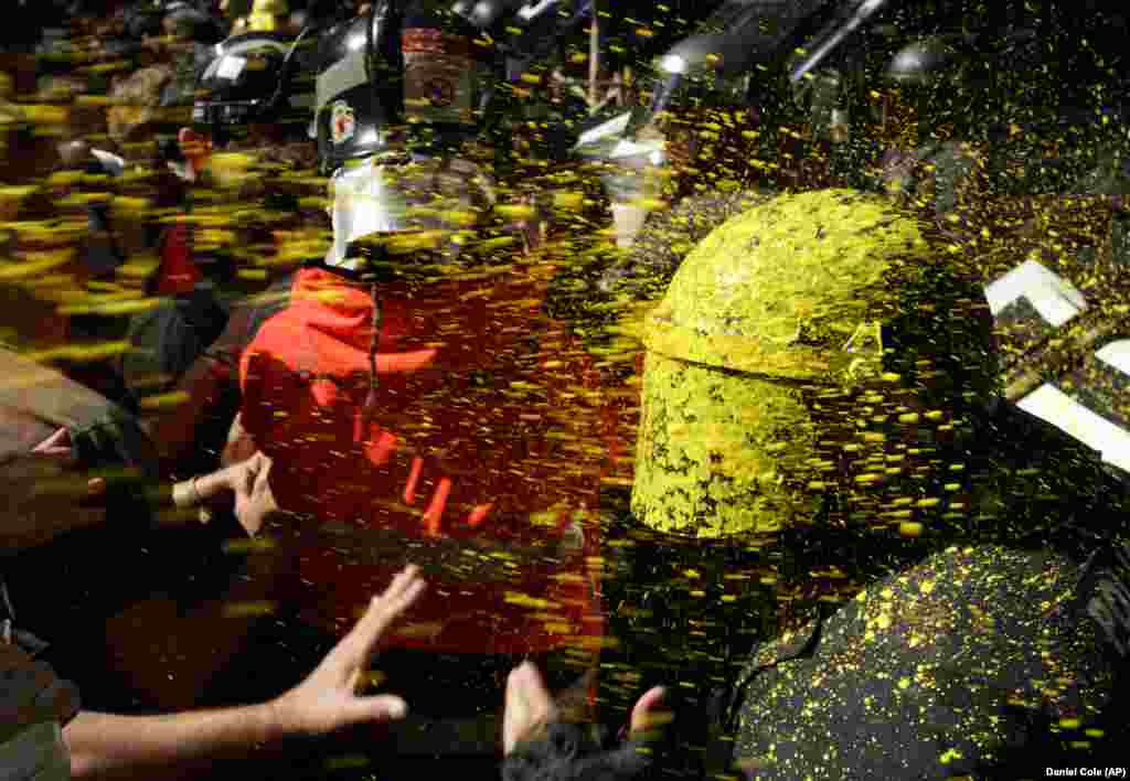 Pro-independence demonstrators throw paint at Catalan police officers during clashes in Barcelona. Catalan separatists clashed with police as tensions increase before the anniversary of the Spanish region&#39;s illegal referendum on secession that ended in violent raids by security forces. (AP/Daniel Cole)​