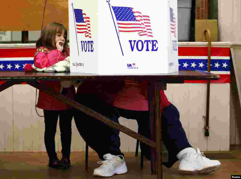 A girl watches as her grandmother votes at the old Town Hall in Bristol, New Hampshire.