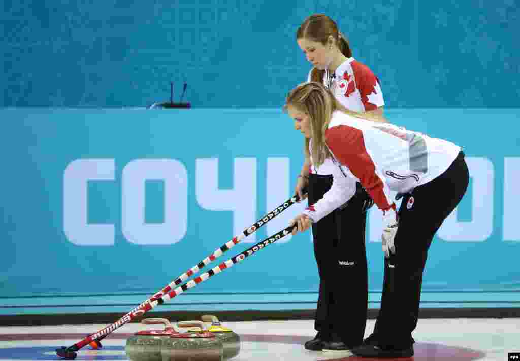 Canada&#39;s Jennifer Jones (bending over) and Kaitlyn Lawes ponder their options during the semifinal match between Great Britain and Canada in the women&#39;s curling competition. (EPA/Tatyana Zenkovich)