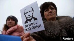 Жанчына з плякатам "Пуцін-акупант" падчас праўкраінскага мітынгу ў Сімфэропалі 11 сакавіка 2014 году, пасьля анэксіі Крыму.