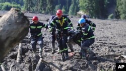 Спасатели несут тело жертвы оползня возле Шови, примерно в 140 километрах к северо-западу от столицы Тбилиси