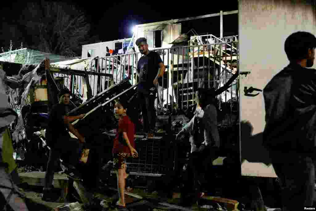 Migrantët qëndrojnë pranë barakave të djegur nga zjarri. Në javët e fundit, mijëra migrantë sirianë dhe afganë kanë kaluar nga Turqia në Greqi.&nbsp;