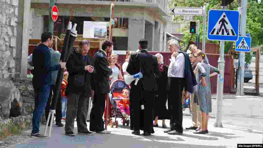 Preotul Ghenadie Valuța, stropind cu aghiazmă locul pe unde a trecut marșul LGBT, pe strada București.