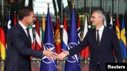 Mark Rutte (left) and Jens Stoltenberg shake hands as Rutte succeeds Stoltenberg as NATO chief at the alliance headquarters in Brussels on October 1.