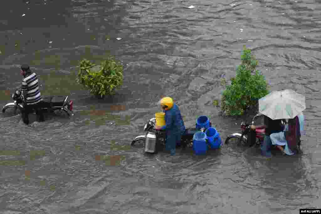 Commuters wade through a flooded street after a heavy rain shower in Lahore, Pakistan, on September 10.