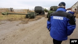 OSCE observers check a column of 15 MT-12 Rapira 100-mm antitank guns being withdrawn by Russian-backed separatists from Donetsk to the village of Zelene on October 28.