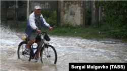 Мужчина едет на велосипеде по затопленной улице в Керчи | Крымское фото дня