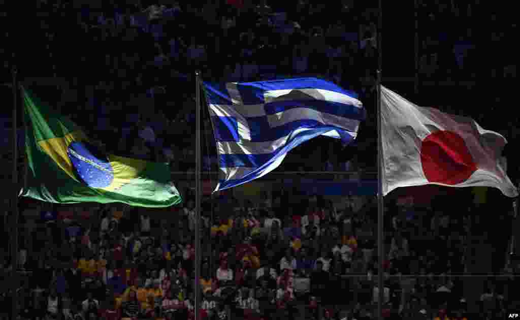 The national flags of Brazil, Greece, and Japan are seen during the closing ceremony. Japan will host the 2020 Olympics in Tokyo.