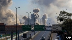 Mașinile circulă pe o autostradă în timp ce norii de fum se ridică după un atac la Teheran, pe 5 martie 2026.