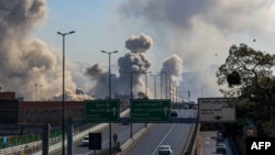 Motorists drive along an expressway as plumes of smoke rise after a strike on Tehran on March 5.
