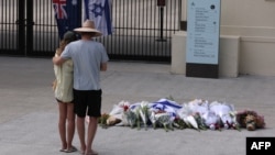 Люди смотрят на цветы, возложенные в память о жертвах стрельбы на пляже Бонди в Сиднее, 15 декабря 2025 года