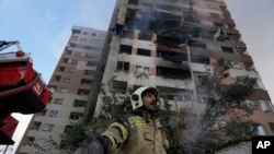 A firefighter calls out his colleagues at the scene of an explosion in a residential compound in northern Tehran on June 13 after Israel launched air strikes on Iran.