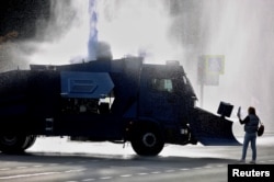 An opposition supporter stands next to a police water cannon during a rally in Minsk on October 4.