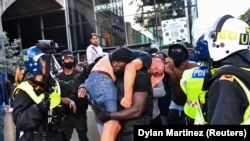 یک معترض سیاه‌پوست در تظاهرات اعتراضی لندن، معترض سفیدپوستی را به دوش می‌کشد که به نقطه امنی منتقل کند. این تظاهرات در واکنش به مرگ جرج فلوید در ۱۳ ژوئن برگزار شد.