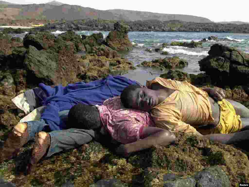Drowned African immigrants lie on the coast in Fuerteventura, one of the Spanish Canary Islands off the coast of Morocco August 1, 2003. Six immigrants drowned, when their flimsy boat ran aground and 15 others disappeared on Thursday when their boat capsized six miles offshore. Fuerteventura is the nearest of the Canary Islands to the African coast and traffickers habitually head for its shores from launching points in southern Morocco, packing their passengers into overloaded boats. REUTERS/Juan Medina 