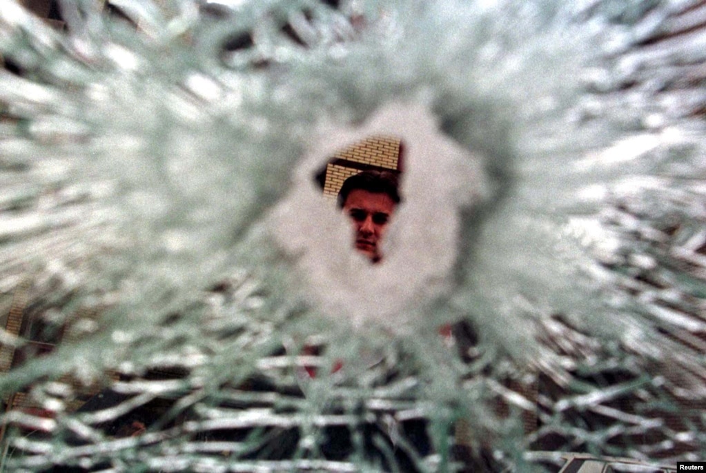 Kosovë: Një burrë duke shikuar një dritare të thyer në Prishtinë më 13 prill 1999, pas sulmeve ajrore të NATO-s mbi caqet serbe në kryeqytetin e Kosovës.Ukrainë: Një grua mund të shihet përmes një çarjeje në xhamin e një makine, e cila u godit nga raketat ruse pranë një blloku apartamentesh në Kiev.