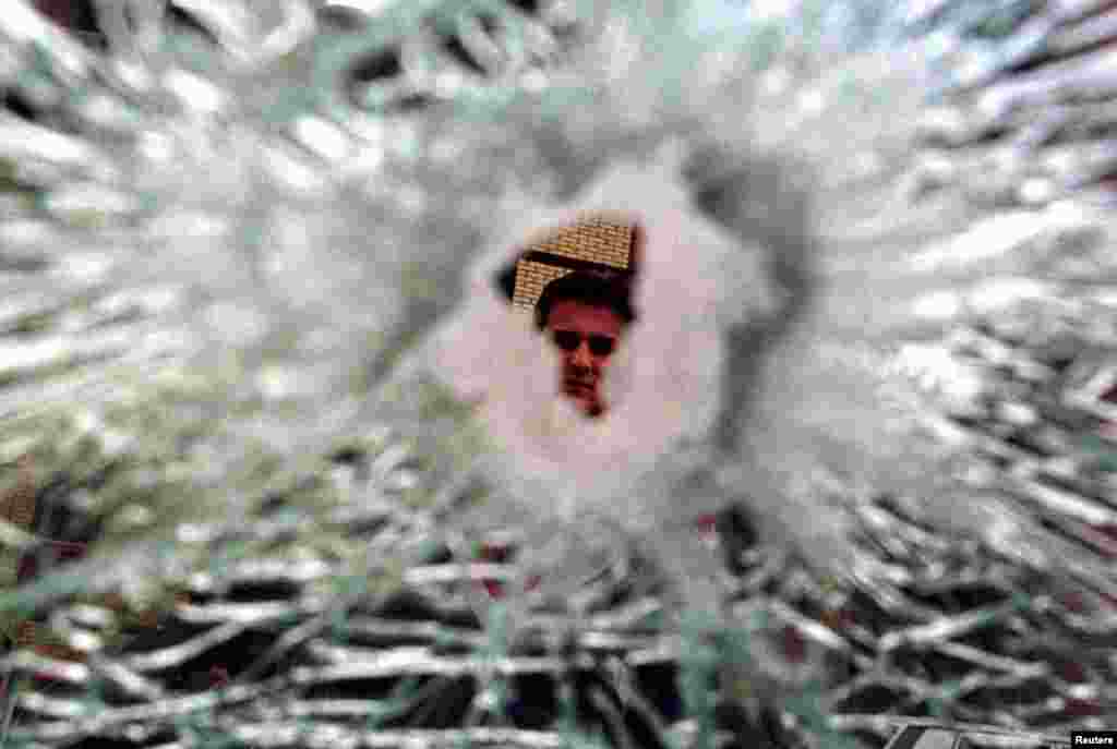 Kosovë: Një burrë duke shikuar një dritare të thyer në Prishtinë më 13 prill 1999, pas sulmeve ajrore të NATO-s mbi caqet serbe në kryeqytetin e Kosovës.Ukrainë: Një grua mund të shihet përmes një çarjeje në xhamin e një makine, e cila u godit nga raketat ruse pranë një blloku apartamentesh në Kiev.