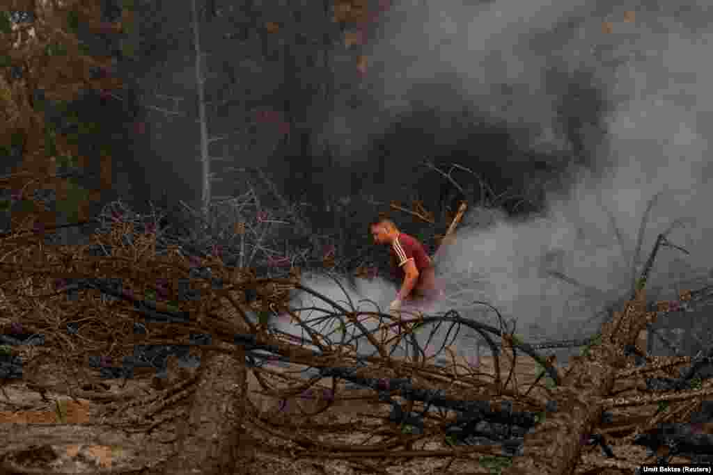 Një vullnetar nga një fshat i afërm duke lagur një pjesë të djegur të një pylli, gjatë një zjarri të egër afër qytezës Kavaklidere, në provincën turke të Muglës. (5 gusht)