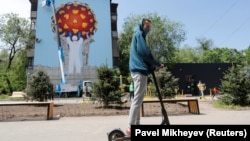 Коронавирус індетіне қарсы күресіп жүрген дәрігер, полицей мен әскери бейнеленген мурал салынған үйдің жанынан өтіп бара жатқан адам. Алматы, 5 мамыр 2020 жыл. Көрнекі сурет.