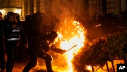 Police attempt to extinguish a fire as supporters of Calin Georgescu protested after in Bucharest.