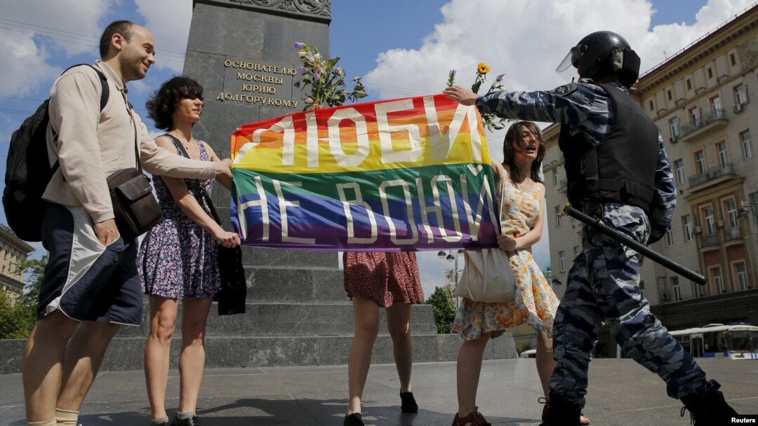 Participants hold a rainbow flag as a policeman stops them during an LGBT community rally in central Moscow on May 30, 2015.