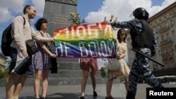 Participants hold a rainbow flag as a policeman stops them during an LGBT community rally in central Moscow on May 30, 2015.