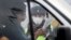 A traffic police officer in a face mask briefs passing drivers 