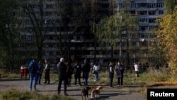 Residents gather in front of an apartment building that was damaged by a Russian missile strike in Kyiv on October 14.