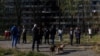 Residents gather in front of an apartment building that was damaged by a Russian missile strike in Kyiv on October 14.