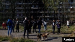 Ýaşaýjylar 14-nji oktýabrda Kiýewde Russiýanyň raketa zarbasyndan zeper ýeten ýaşaýyş jaýynyň öňünde ýygnanýarlar.