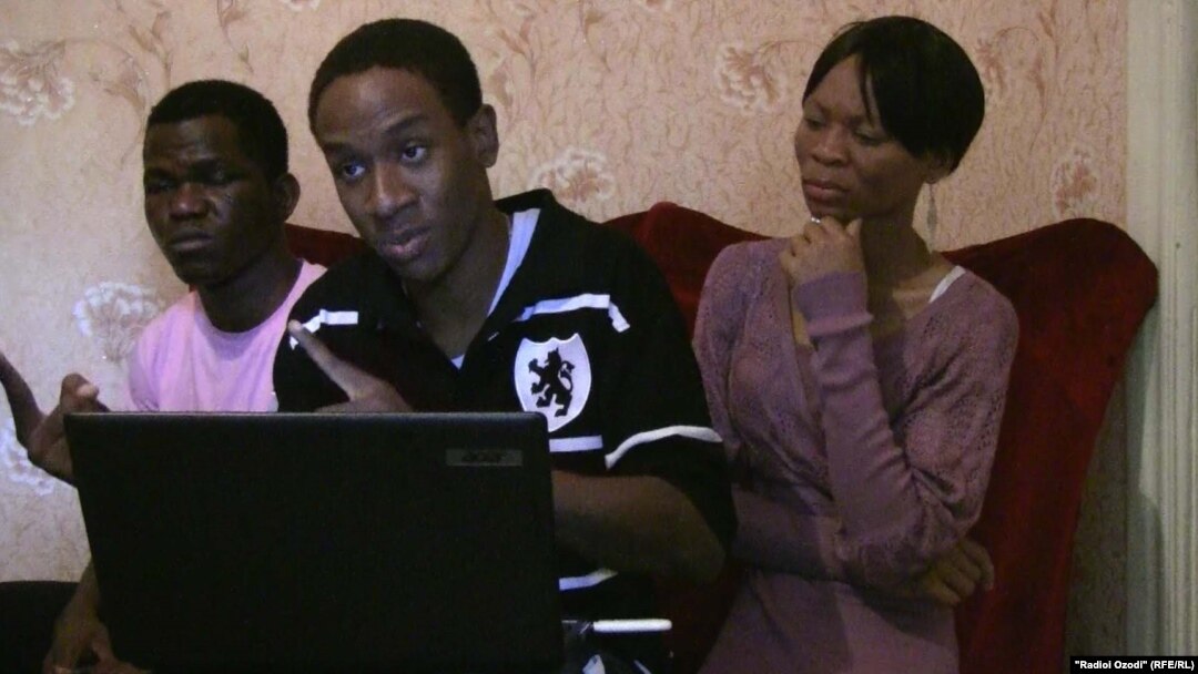 Aspiring Nigerian soccer player Dennis Tahgbok (center) discusses his situation from a flat in Dushanbe.