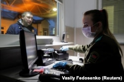 A Belarusian border guard wears a face mask and gloves to protect herself from the coronavirus early in the pandemic. Belarus would later close off its borders to foreigners.