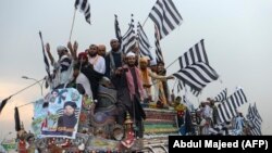 Supporters of the Islamist Jamiat Ulema-e-Islam (JUI-F) wave party flags atop a vehicle as they take part in an anti-government protest on October 31. 