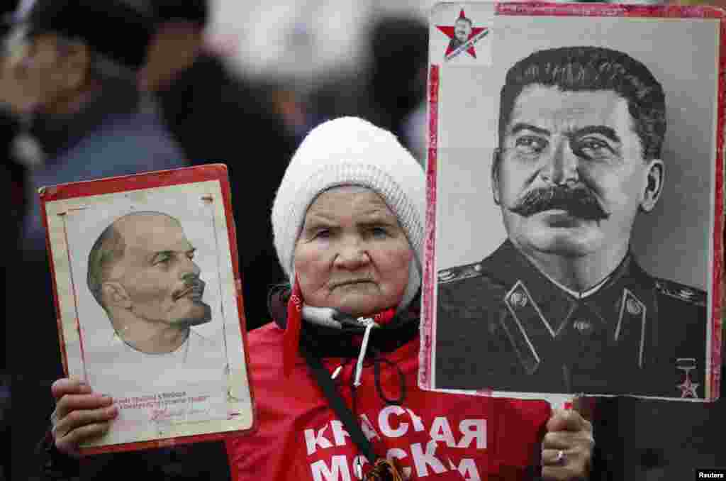 A supporter of the Russian Communist Party holds portraits of Soviet state leaders Vladimir Lenin (left) and Josef Stalin during a procession to mark the Defender of the Fatherland Day in central Moscow on February 23. (Reuters/Maxim Zmeyev)