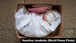 Світлина польської фотографині Кароліни Джондерко, яка отримала другу нагороду в категорії «Довгострокові проєкти» на конкурсі World Press Photo Contest 2021, показує, що лялька, яка «відродилася», лежить упакована і готова до відправлення новому «батькові»