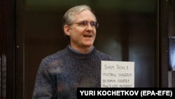 Paul Whelan holds up a sign denouncing the legal proceedings against him as he stands inside the defendant's cage before hearing the verdict of his espionage trial at the Moscow City Court on June 15.