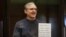Paul Whelan holds up a sign denouncing the legal proceedings against him as he stands inside the defendant's cage before hearing the verdict of his espionage trial at the Moscow City Court on June 15.