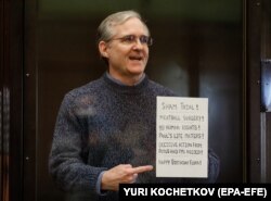 Пол Уилан держит плакат, осуждающий судебные разбирательства против него, когда он стоит в клетке перед тем, как заслушать приговор по своему делу в Московском городском суде, Россия, 15 июня 2020 года.