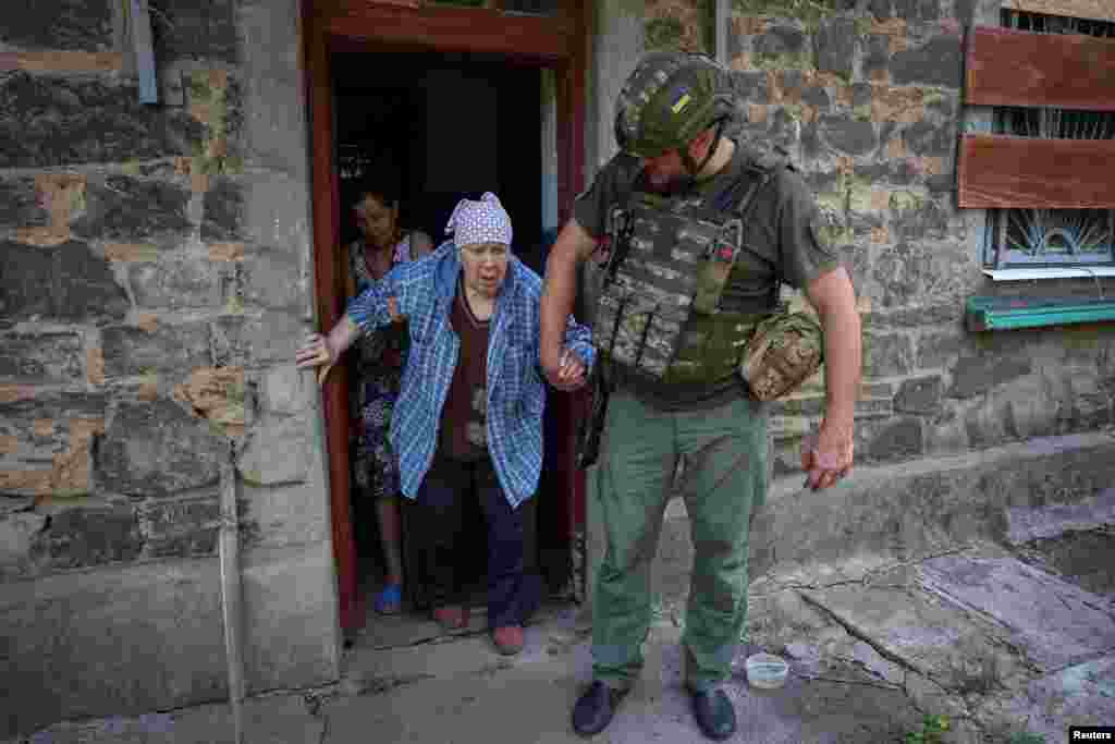 A police officer evacuates a woman from her house in the frontline town of Kostyantynivka, Donetsk region, Ukraine.