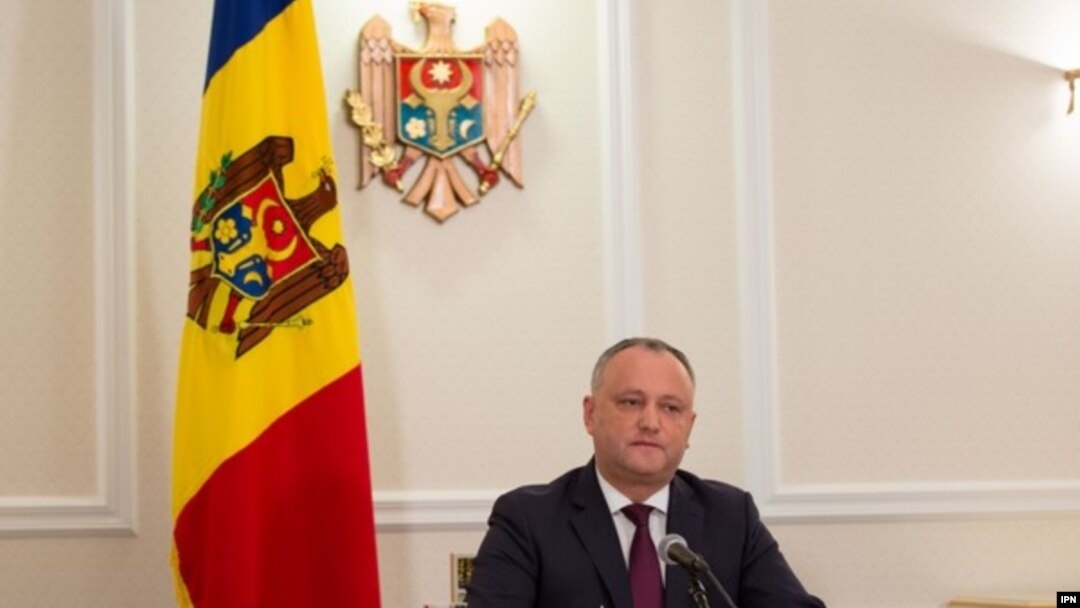 A file photo of Moldovan President Igor Dodon with the country's current tricolor flag in the background.