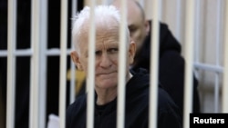 Nobel Peace Prize laureate Ales Byalyatski, who co-founded the Vyasna (Spring) human rights group, sits inside a defendants' cage during a court hearing in Minsk on January 5. 