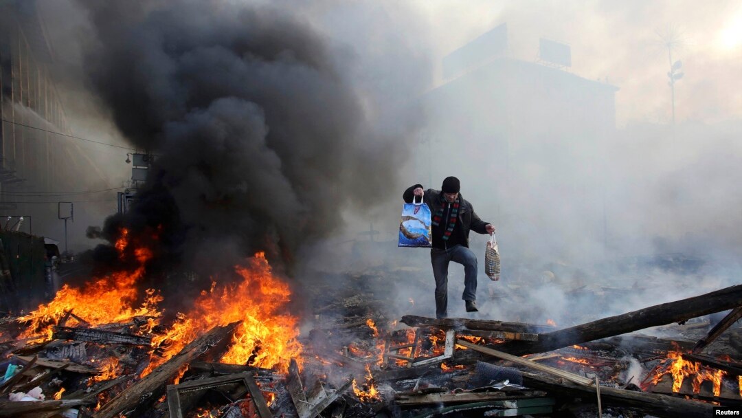 A man walks amid burning remains of barricades on Independence Square in Kyiv on February 21.