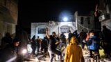 EDITORS NOTE: Graphic content / People gather in front of a building hit by an Israeli strike on Rafah in the southern Gaza strip on December 28, 2023, as battles continue between Israel and the Palestinian Hamas movement. (Photo by Mahmud HAMS / AFP)